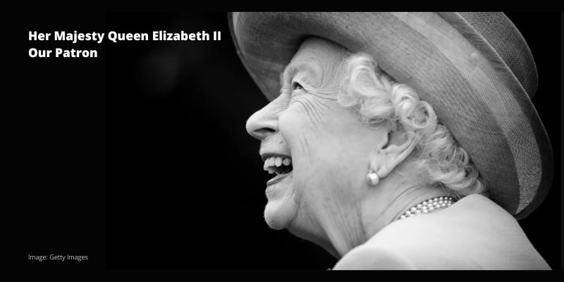 A black and white portrait of Her Majesty The Queen laughing.
