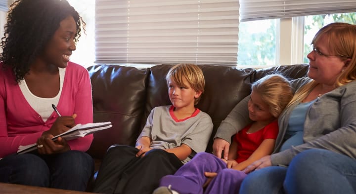 A family sit with their social worker on the sofa at home. 