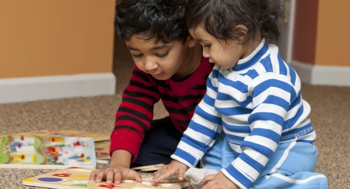 Two small preschool children playing with puzzles.