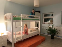 Liliana and Marcel sit on their new bunkbeds in their bedroom